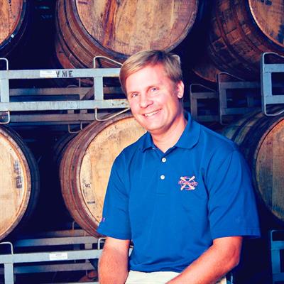  Brett VanderKamp, President and Co-founder New Holland Brewing, sitting in front of wooden barrels smiling